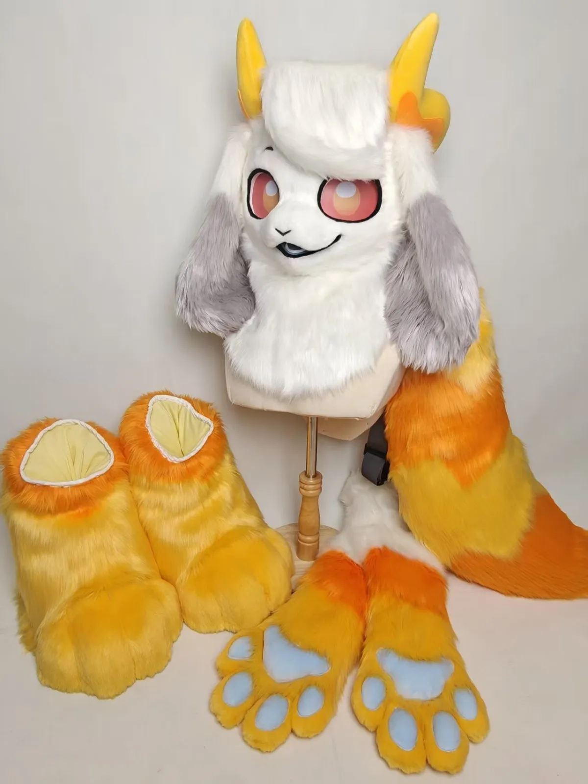 White horned creature fursuit with orange & yellow paws